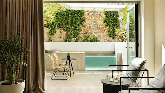 Moderne rom med sittegruppe og utsikt mot privat basseng og vegg med klatreplante. (AI-generert tekst)