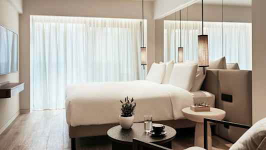 Et moderne hotellrom med en stor seng, hvite laken og minimalistisk innredning. (AI-generert tekst)