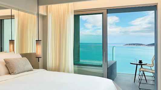 Hotellrom med havutsikt gjennom balkongdøren. (AI-generert tekst)