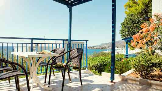 En terrasse med stoler og et bord, havutsikt og grøntområder. (AI-generert tekst)