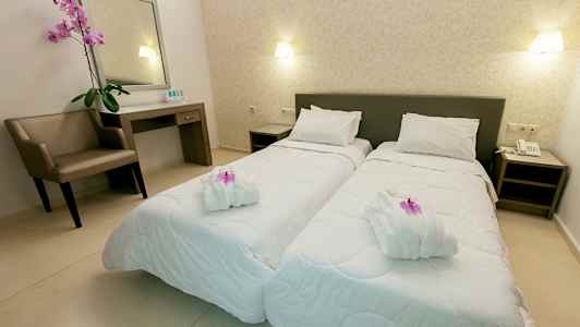 To enkeltsenger i et velorganisert hotellrom med en stol, et skrivebord og dekorative elementer. (AI-generert tekst)