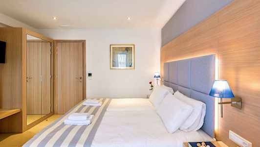 Et hotellrom med en dobbeltseng, tredetaljer, blå lamper og et speilskap. (AI-generert tekst)