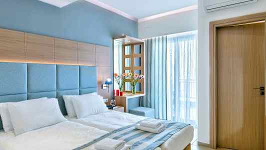 Et hotellrom med en dobbeltseng med hvitt sengetøy, trepaneler og blå detaljer. (AI-generert tekst)