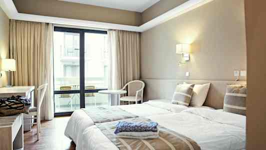 Hotellrom med to enkeltsenger, skrivebord og balkong. (AI-generert tekst)