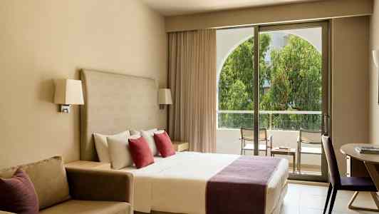 Hotellrom med dobbeltseng, sofa og utgang til balkong. (AI-generert tekst)