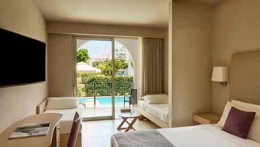 Et hotellrom med en dobbeltseng, en skriveplass og en ekstra seng. Utenfor vises en terrasse og et basseng. (AI-generert tekst)