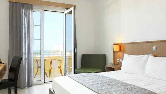 Et hotellrom med en dobbeltseng og en balkong med utsikt. (AI-generert tekst)