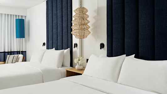 To senger med hvitt sengetøy på et hotellrom. (AI-generert tekst)