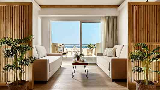 Moderne stue med to sofaer og utsikt mot terrasse og hav. (AI-generert tekst)