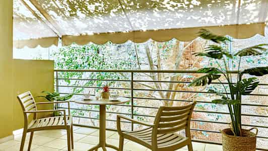 En terrasse med et bord og to stoler nær et rekkverk, dekorert med planter. (AI-generert tekst)