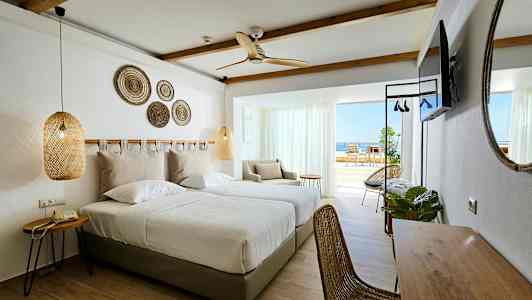 Hotellrom med to enkeltsenger, sittegruppe og balkong med havutsikt. (AI-generert tekst)