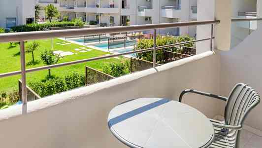 Utsikt fra en balkong med utsikt over en frodig hage og bassengområde. (AI-generert tekst)