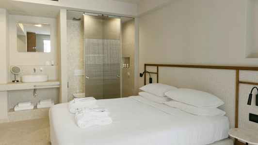 Moderne innredet hotellrom med en dobbeltseng, servant og glassdør til badet. (AI-generert tekst)