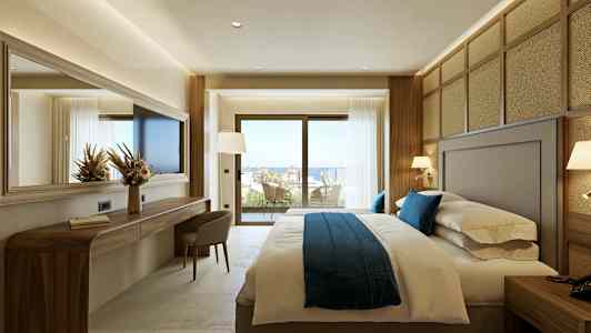 Et hotellrom med en stor seng og vinduer som åpner opp til en balkong med utsikt. (AI-generert tekst)