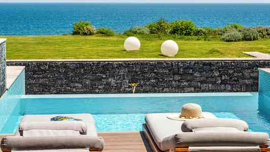 To solsenger ved et basseng med utsikt over havet. (AI-generert tekst)