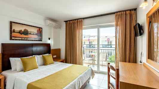 Interiør av hotellrom med en seng, skrivebord og balkong. (AI-generert tekst)