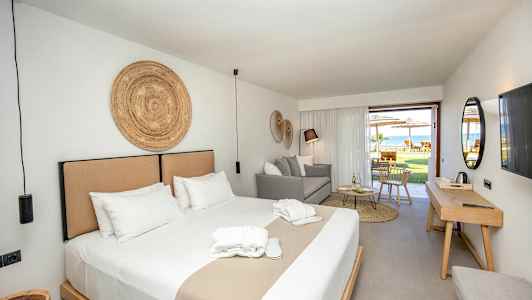 En hotellsuite med dobbeltseng, sitteplass og utgang til en møblert terrasse. (AI-generert tekst)