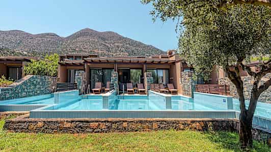 Private bassengområder foran ferieboliger med fjell i bakgrunnen. (AI-generert tekst)