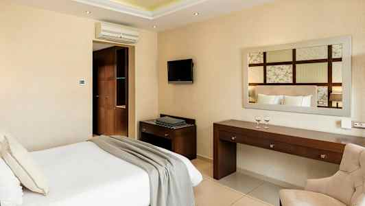 Et hotellrom med en seng, skrivebord, stol og vegg-TV. (AI-generert tekst)