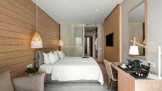 Et lyst og moderne hotellrom med en stor dobbeltseng, et skrivebord og en dekorativ marmorpanel på veggen. (AI-generert tekst)