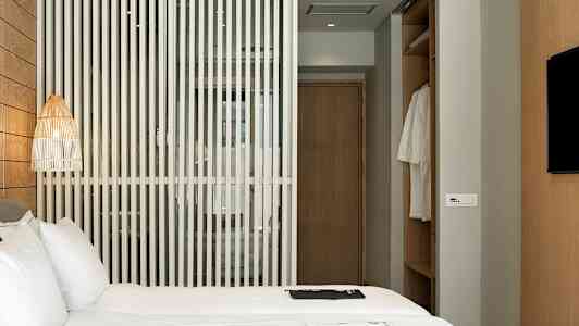 Hotellrom med en seng, en trevegg og en garderobe. (AI-generert tekst)