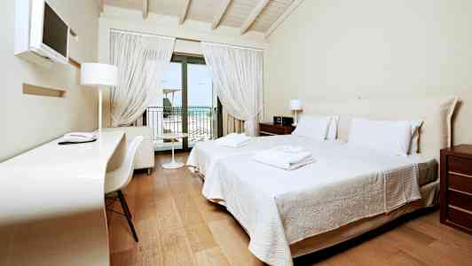 Et hotellrom med to enkeltsenger, et skrivebord og en balkong med utsikt. (AI-generert tekst)