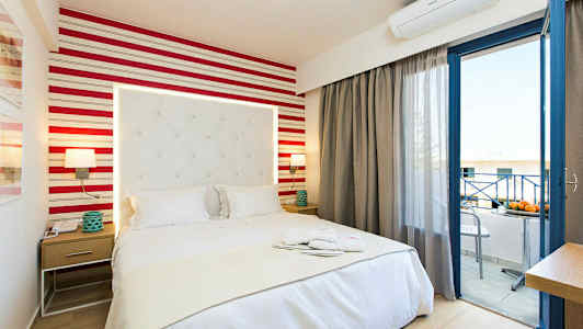 Et hotellrom med en seng, nattbord og åpen balkongdør. (AI-generert tekst)