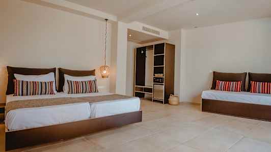 Et hotellrom med en stor seng, dekorative puter og en åpen garderobe. (AI-generert tekst)