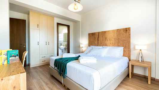 Et lyst hotellrom med dobbeltseng, tredetaljer og er velstelt. (AI-generert tekst)