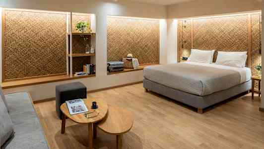 Et hotellrom med en stor seng, en sitteplass og hyller på veggen. (AI-generert tekst)