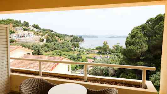 Utsikt fra en balkong over grøntområder, bygninger og en bukt. (AI-generert tekst)