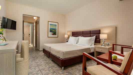 Et hotellrom med en dobbeltseng, en lenestol og et bord. (AI-generert tekst)