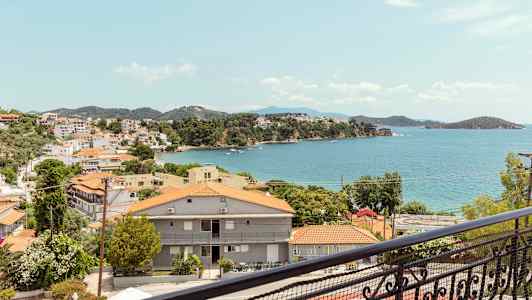 Utsikt over en kystby med røde tak og havet i bakgrunnen. (AI-generert tekst)