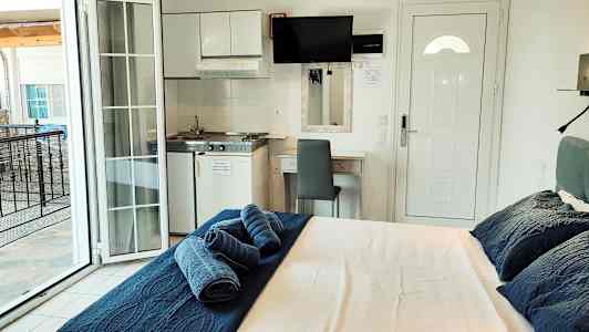 Et hotellrom med en seng, et lite kjøkkenområde og en balkong. (AI-generert tekst)