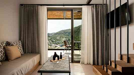 Rom med interiør og utsikt over landskapet gjennom en glassdør. (AI-generert tekst)