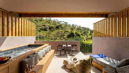 En uteplass med boblebad, sitteplasser og utsikt over grønn natur. (AI-generert tekst)