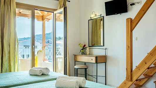 Et hotellrom med to enkeltsenger, et speil med et skrivebord, en balkongdør og en veggmontert TV. (AI-generert tekst)