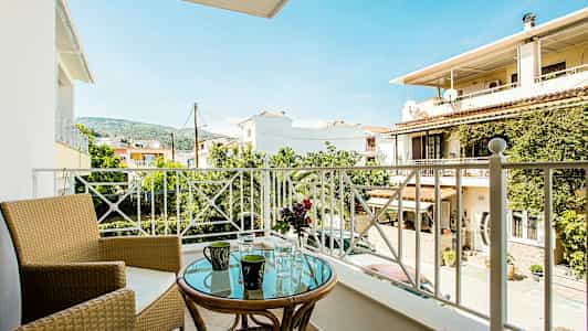 Balkong med utsikt over bolighus, trær og fjell. (AI-generert tekst)