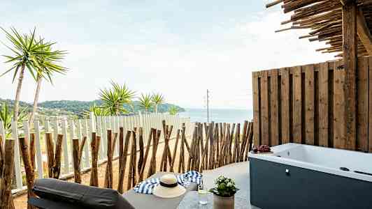 Privat veranda med havutsikt, solseng og badekar. (AI-generert tekst)