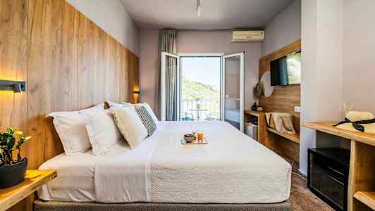 Hotellrom med en dobbeltseng, dekorert med trepaneler og en balkong med utsikt. (AI-generert tekst)