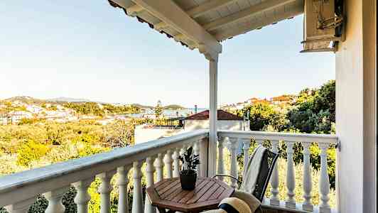 En balkong med utsikt over et landskap med hus og trær. (AI-generert tekst)