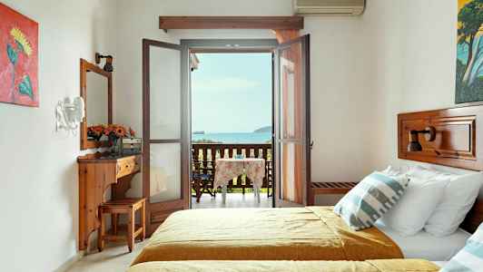 Et hotellrom med to senger og en møblert balkong med utsikt over havet. (AI-generert tekst)