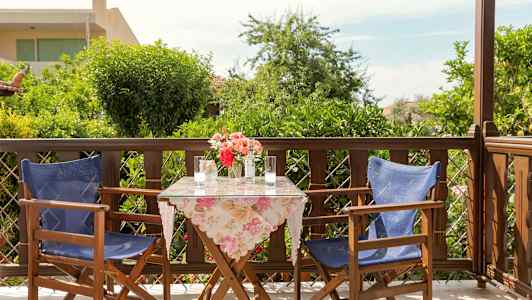 En uteplass med to stoler og et bord med blomster. (AI-generert tekst)