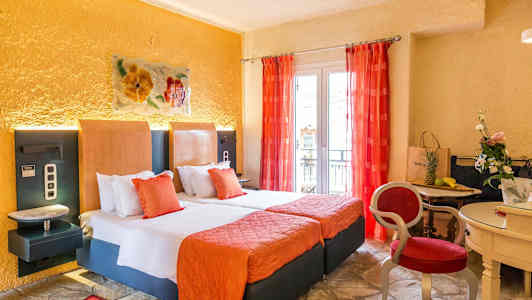 Et hotellrom med to senger, oransje interiør og røde gardiner, samt et lite bord med stoler og dekorasjoner. (AI-generert tekst)