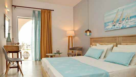 Utsikt over et hotellrom med en seng, skrivebord og stoler, dekorert med blå og gule farger. (AI-generert tekst)