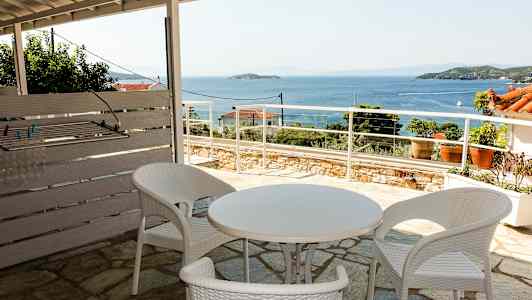 Utendørsområde med hvite plastmøbler og utsikt over havet. (AI-generert tekst)