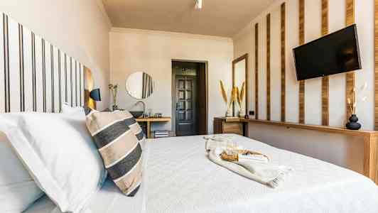 Et moderne hotellrom med en oppredd seng, dekorative trepaneler og en TV på veggen. (AI-generert tekst)