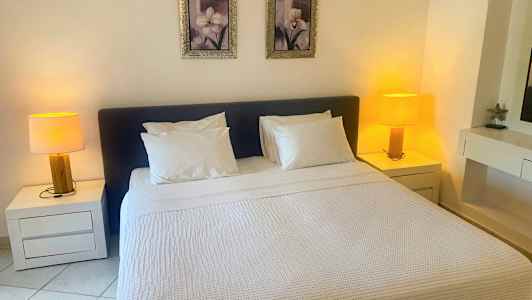 Et soverom med en dobbeltseng, to nattbord med lamper og to bilder over sengen. (AI-generert tekst)