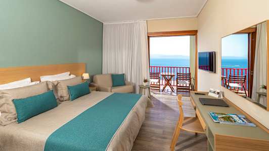 Hotellrom med dobbeltseng og balkong med havutsikt. (AI-generert tekst)