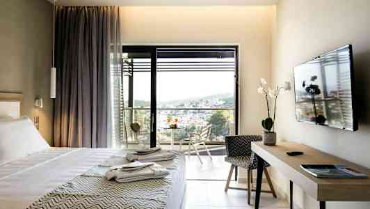 Hotellrom med seng, TV, skrivebord og balkong med utsikt. (AI-generert tekst)